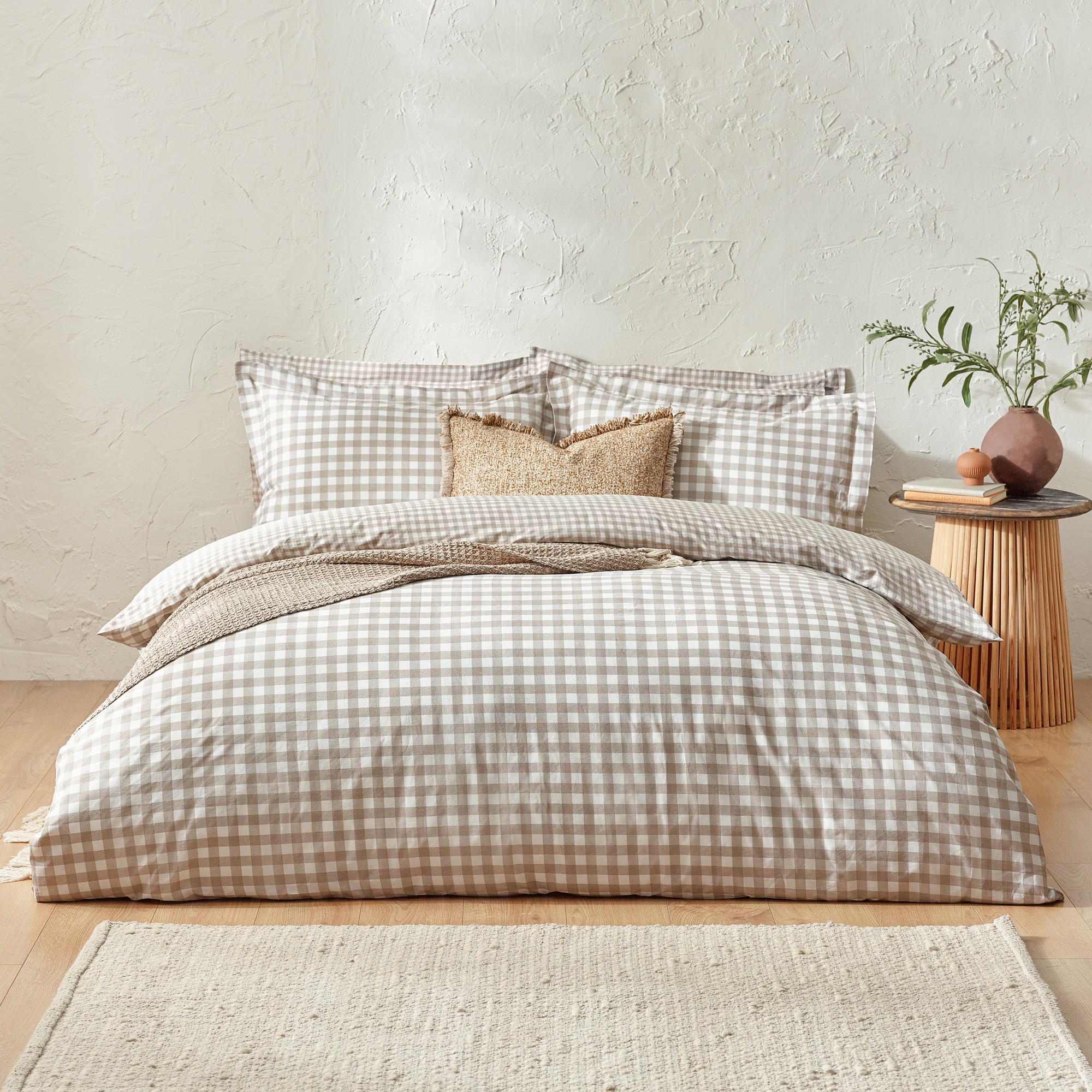 Natural-colored 100% cotton duvet cover set featuring a classic check pattern, complemented by matching pillowcases and a textured decorative cushion, styled on a wooden bed frame.