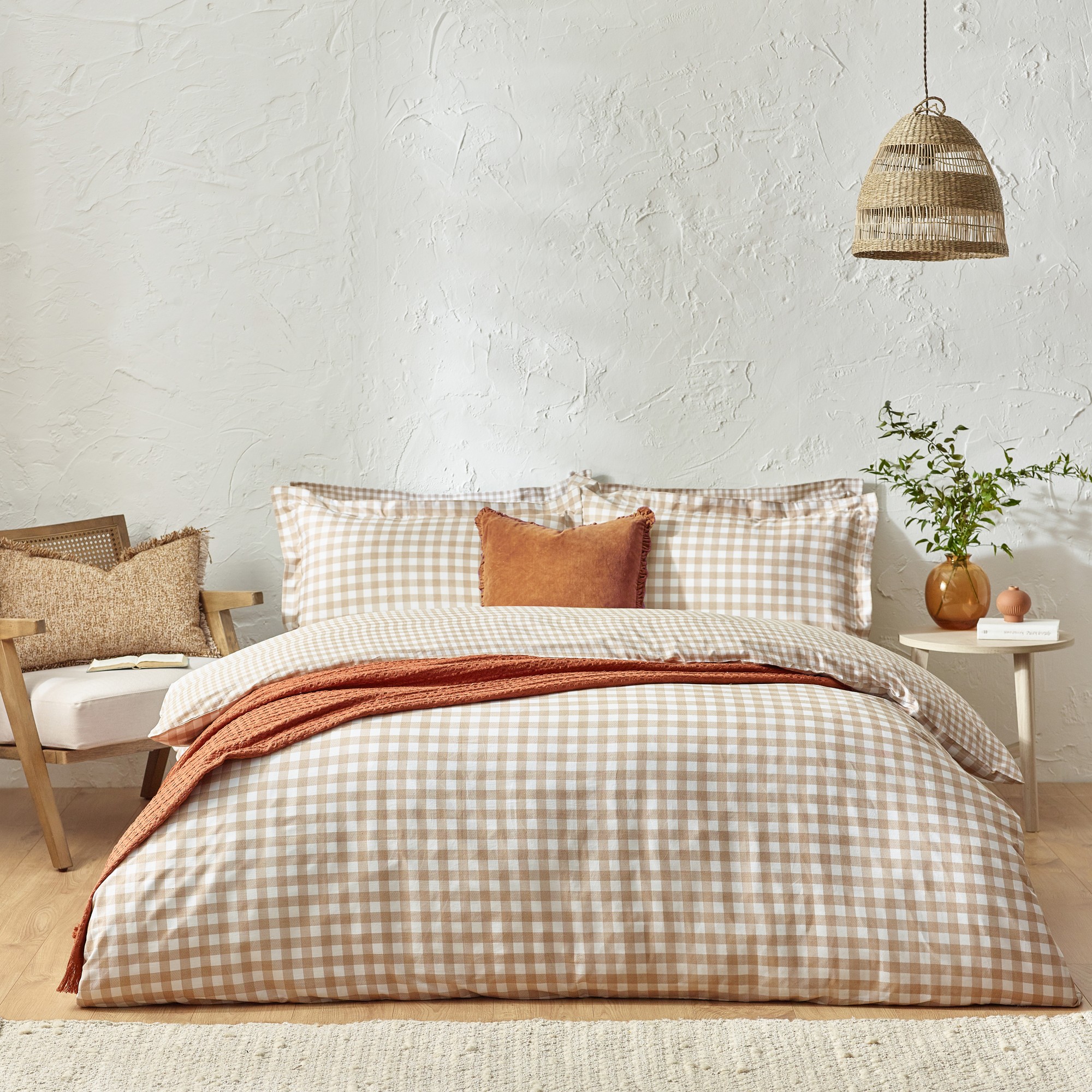 Beige checkered 100% cotton duvet cover set in king size, featuring a textured pattern, complemented by a rust-colored throw and decorative pillows on a cozy bed.