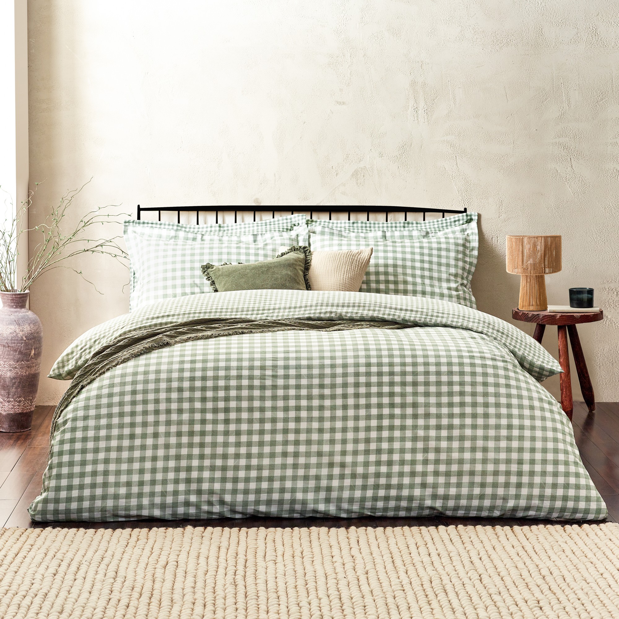 Reversible duvet cover set featuring a green and white gingham check pattern, accompanied by matching pillow shams and decorative cushions on a wooden bed frame.
