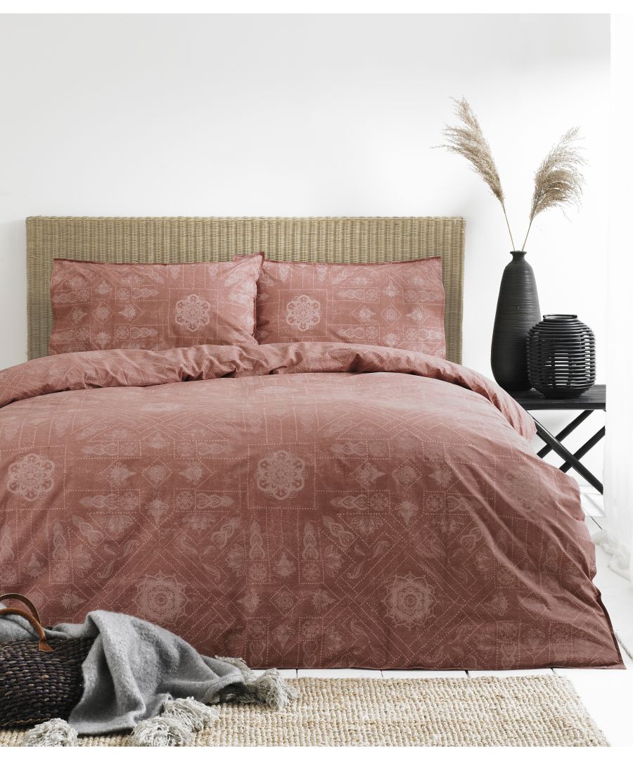 Bohemian duvet set in red clay, featuring intricate patterns, paired with two matching pillowcases, displayed on a textured bed against a neutral backdrop.