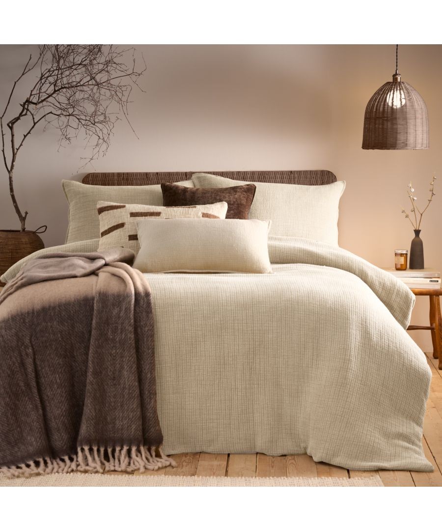 Beige acid-washed duvet set with textured fabric, complemented by brown and cream decorative pillows, a cozy brown throw, and a warm, inviting bedroom ambiance.