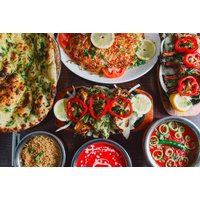Indian dining set with naan, rice, curry, and garnished dishes, featuring vibrant vegetables and lemon slices.