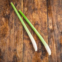 Fresh green and white lemongrass stalks on rustic wooden surface.