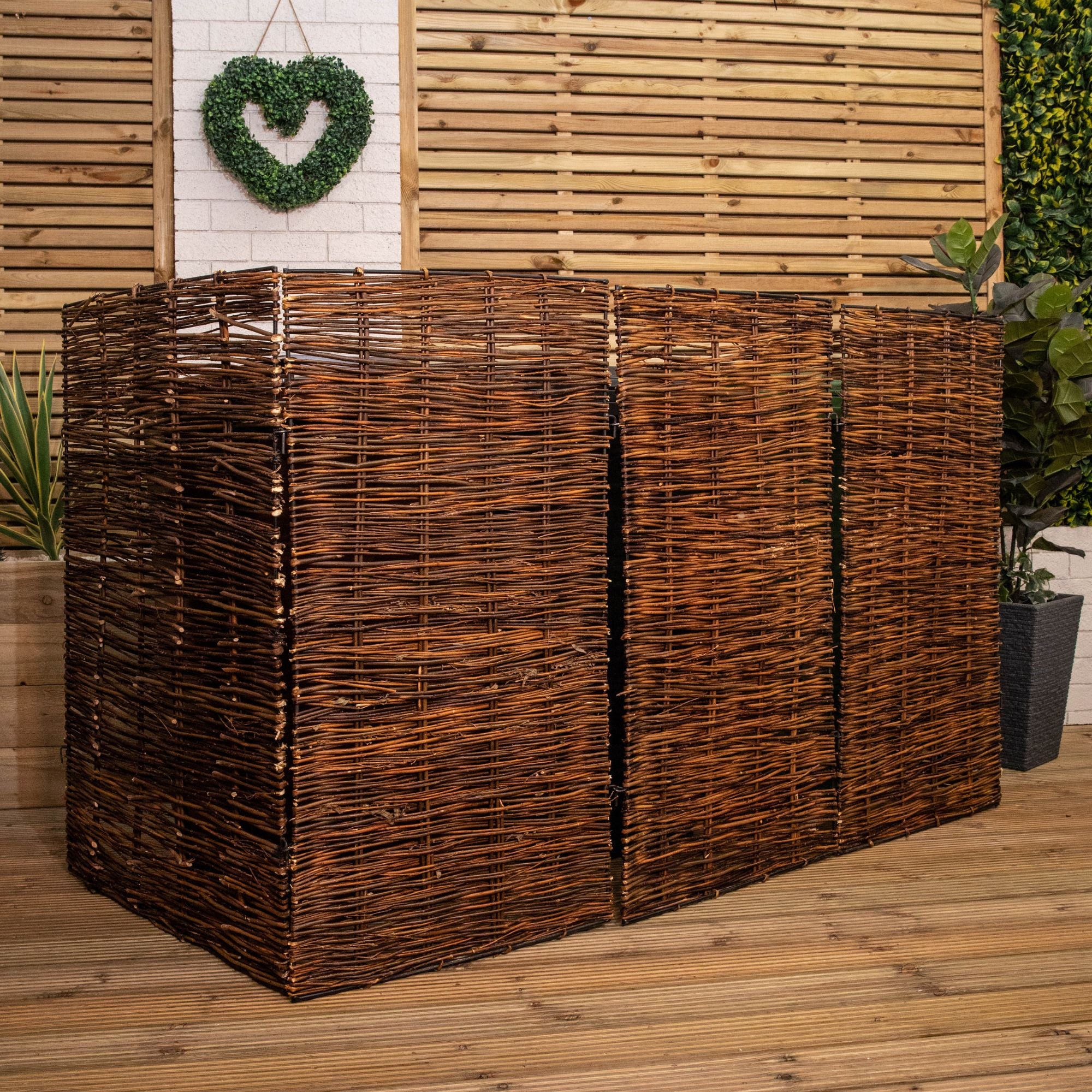 Brown willow wheelie bin screen hideaway, measuring 1.16m x 1.83m, featuring a woven design with three sections, set against a wooden backdrop and greenery.