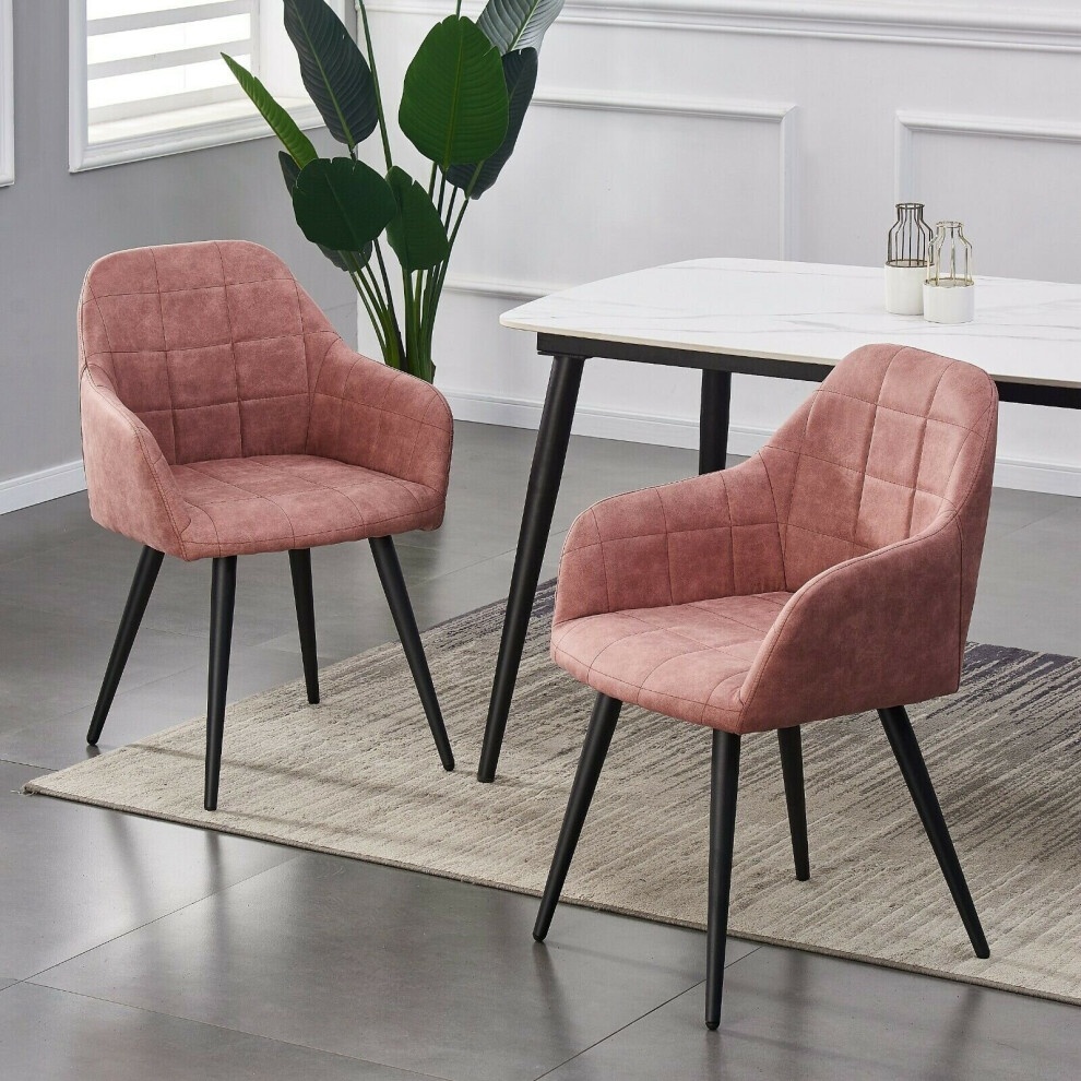 Set of 2 pink faux suede leather dining chairs with quilted design, featuring black legs, placed beside a white table on a textured rug in a modern interior.