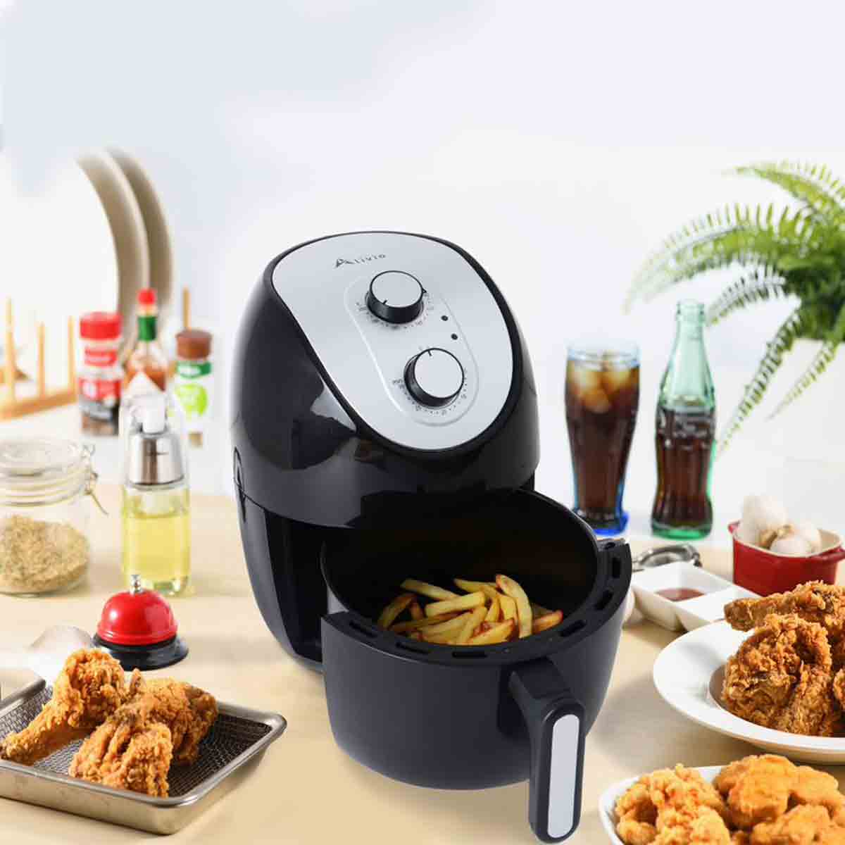 Black Hirix Alivio 3L air fryer with a sleek design, featuring a silver control panel, two knobs, and a detachable basket filled with golden fries, surrounded by food and beverages.