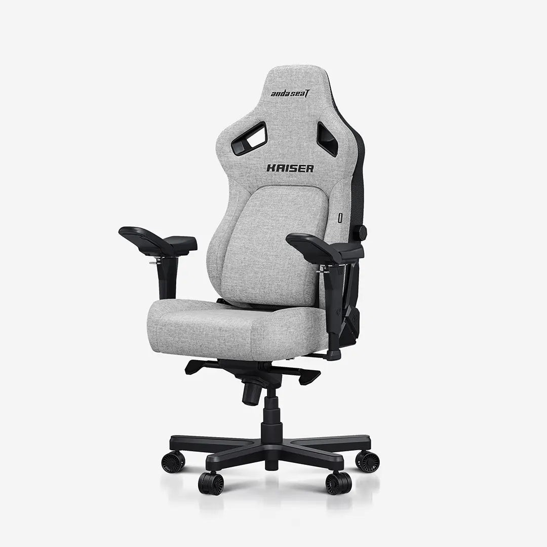 Premium gaming chair in ash gray linen fabric, featuring adjustable armrests, ergonomic design, and a high backrest with "Kaiser" branding, mounted on a five-star base with wheels.