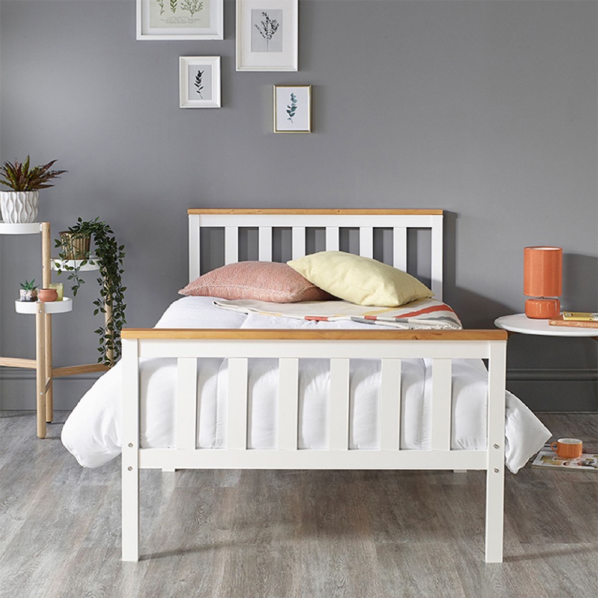 Solid white wooden bed frame with a natural wood headboard, featuring a slatted design, set against a grey wall, with decorative pillows and plants in the background.