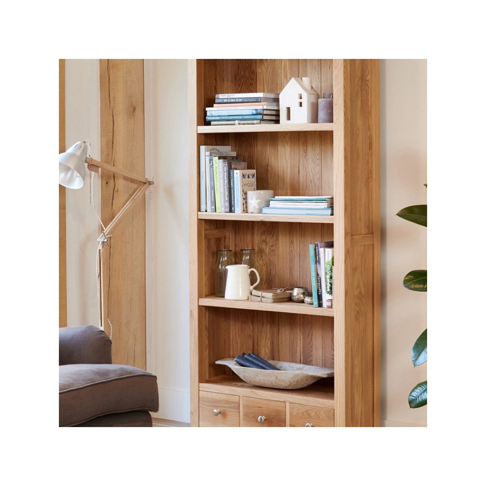 Large oak bookcase in brown featuring three drawers, open shelving, and a natural wood finish, ideal for displaying books and decorative items.