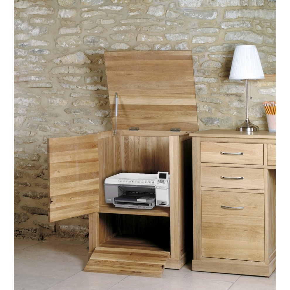 Brown oak printer cupboard with a hinged top, featuring a spacious interior for a printer, two open compartments, and a side drawer, set against a stone wall backdrop.