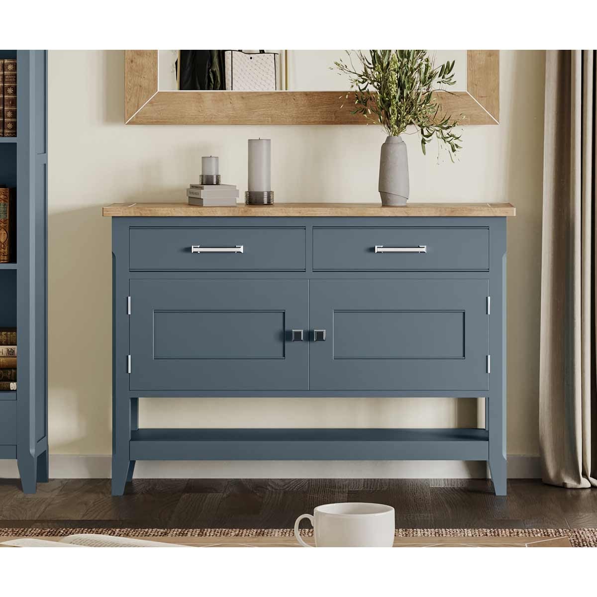 Cobalt blue sideboard with two drawers and a central cabinet, featuring a light wood top, silver handles, and a minimalist design, complemented by a decorative vase and candles.