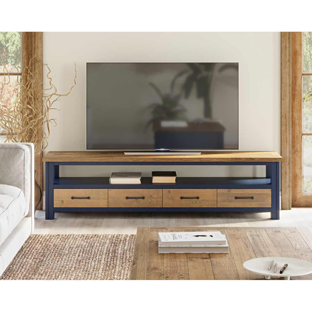 Super sized widescreen television cabinet in blue and natural wood, featuring a spacious top, open shelf, and four drawers with metal handles for storage.