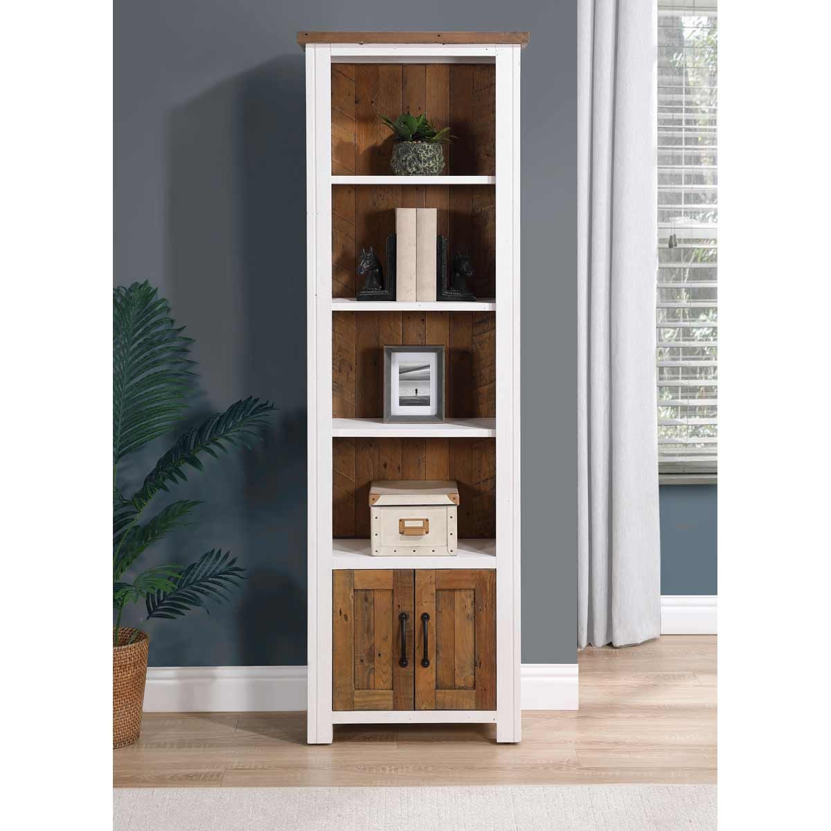Narrow bookcase featuring a white frame with wooden shelves and a rustic brown cabinet at the bottom, showcasing a blend of modern and traditional design elements.