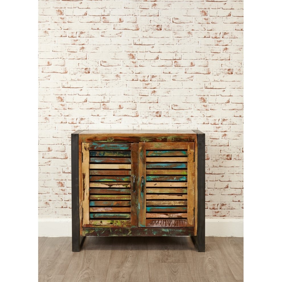 Brown wooden sideboard with two slatted doors featuring a colorful, distressed finish, set against a white brick wall.
