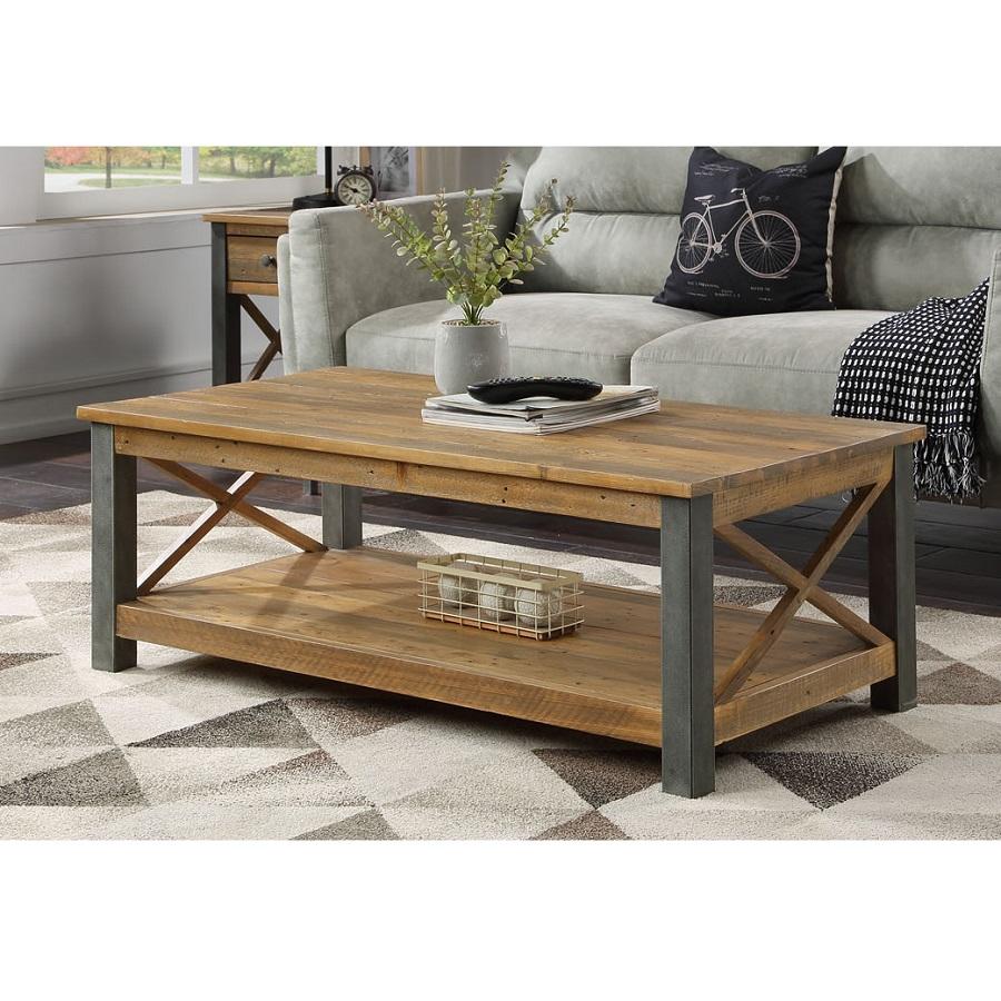 Reclaimed brown wood coffee table with a sturdy gray metal frame, featuring a lower shelf and crossed side supports, set in a cozy living room with a patterned rug.