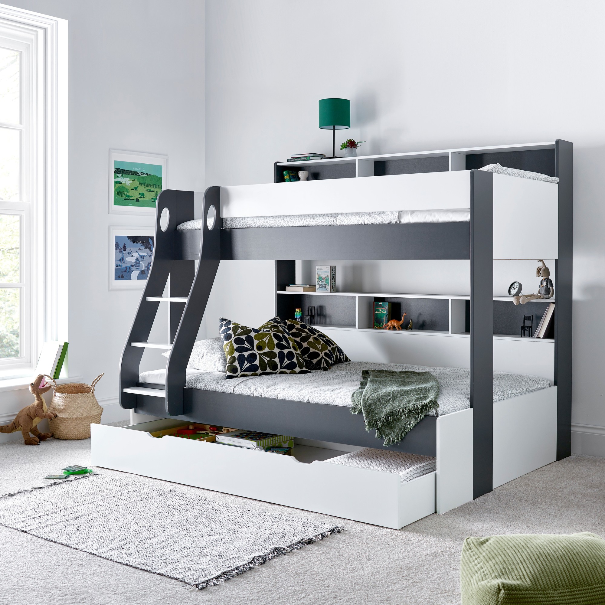 Grey triple sleeper bunk bed with a small double bottom, featuring a sturdy frame, built-in shelves, and a soft mattress, set against a light room with decorative accents.