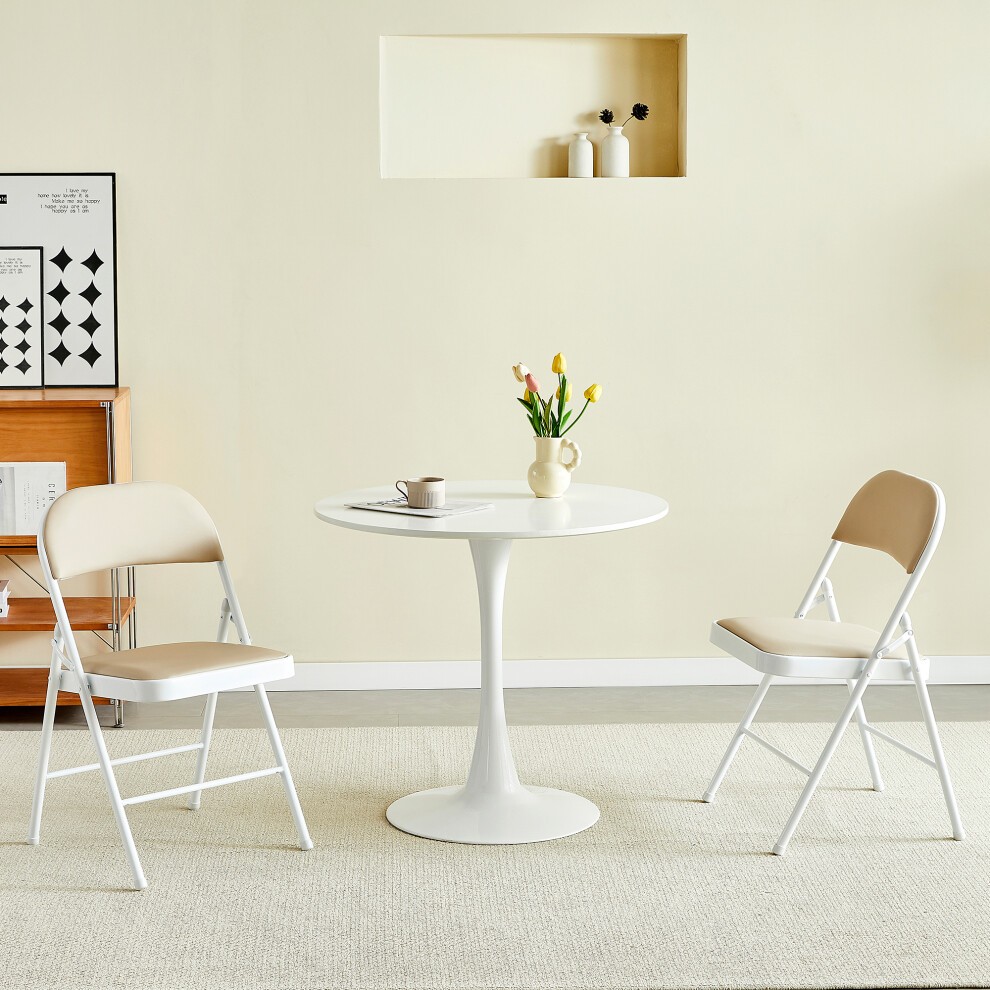 Set of 2 folding dining chairs with a white metal frame and padded beige seats, positioned around a round white table in a light-colored room.