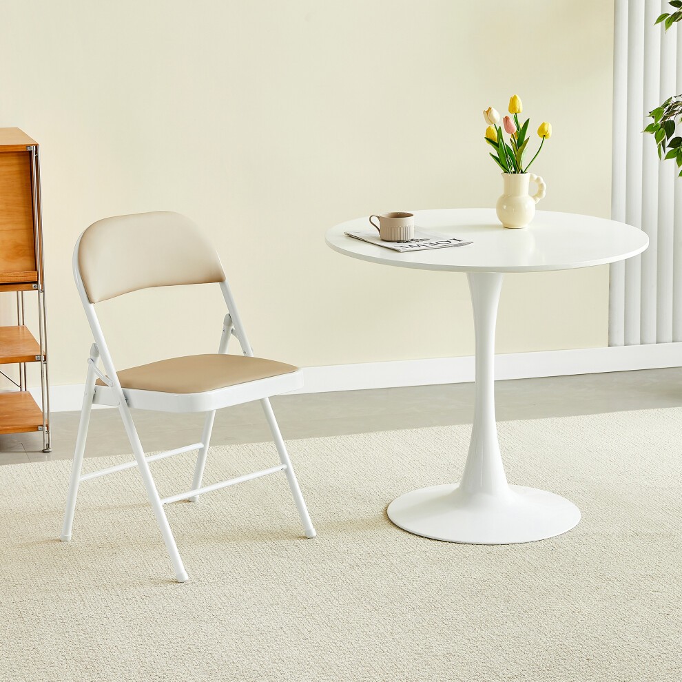Single folding dining chair with a white metal frame and a padded beige seat, positioned next to a round white table with a vase of tulips.