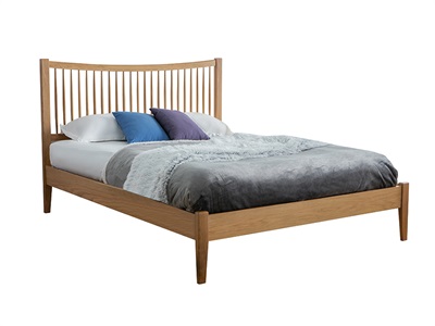 Light brown wooden double bed with a slatted headboard, featuring a white mattress and grey throw blanket, accented by blue and purple pillows.