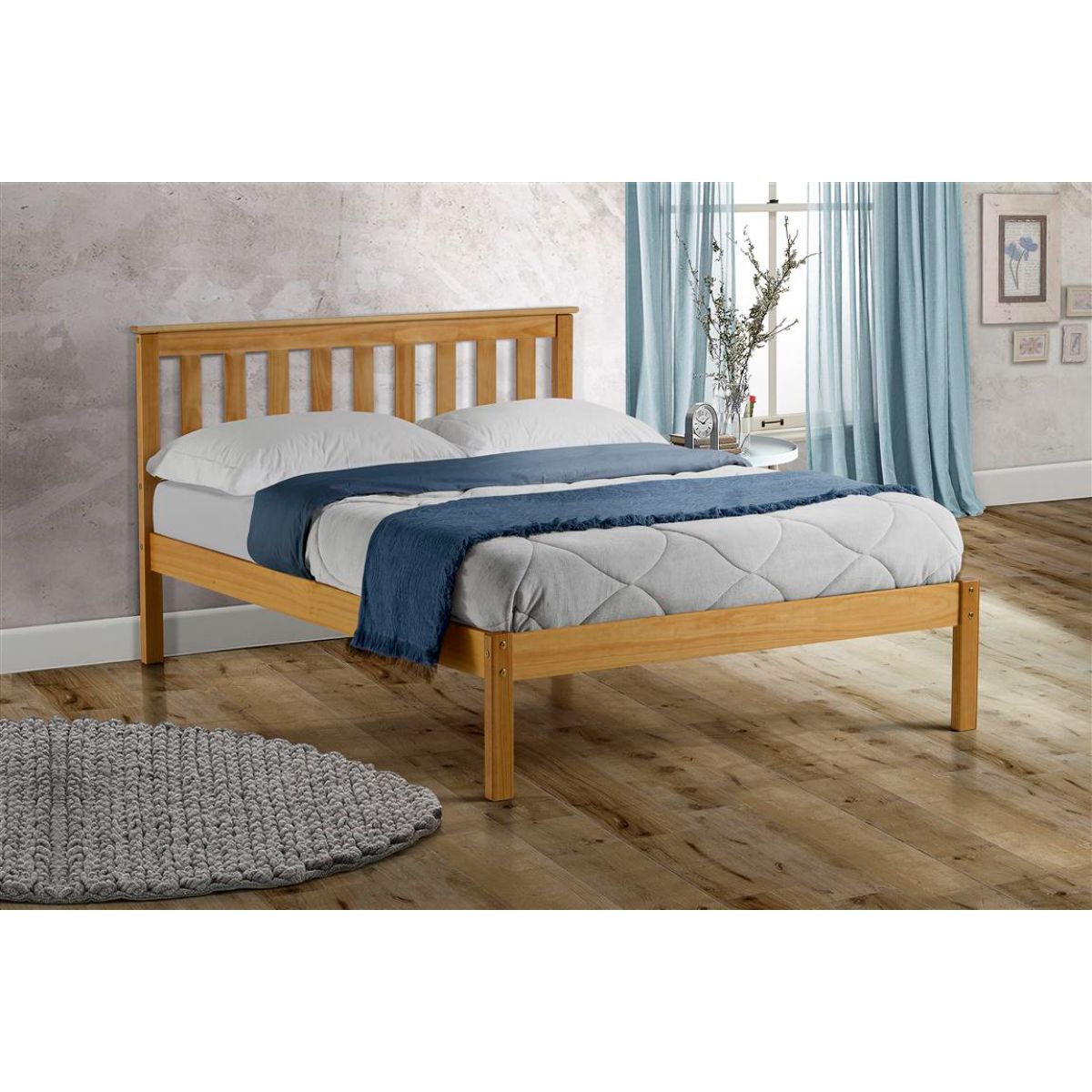 Brown wooden king-sized bed with a slatted headboard, featuring a simple design and sturdy legs, complemented by a light grey quilted mattress and blue throw blanket.