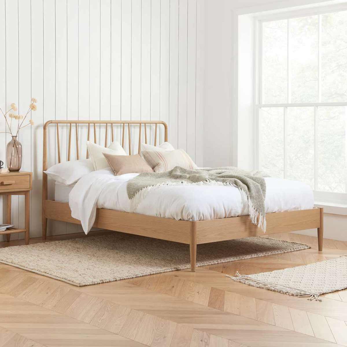 Light brown Jesper bed frame by Birlea, featuring a slatted headboard, clean lines, and a low profile, complemented by a cozy white bedding set and decorative pillows.