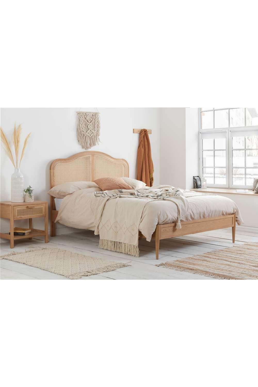 Brown wooden bed frame with a rattan headboard, featuring a minimalist design, complemented by soft bedding and a cozy, neutral color palette in a stylish room setting.