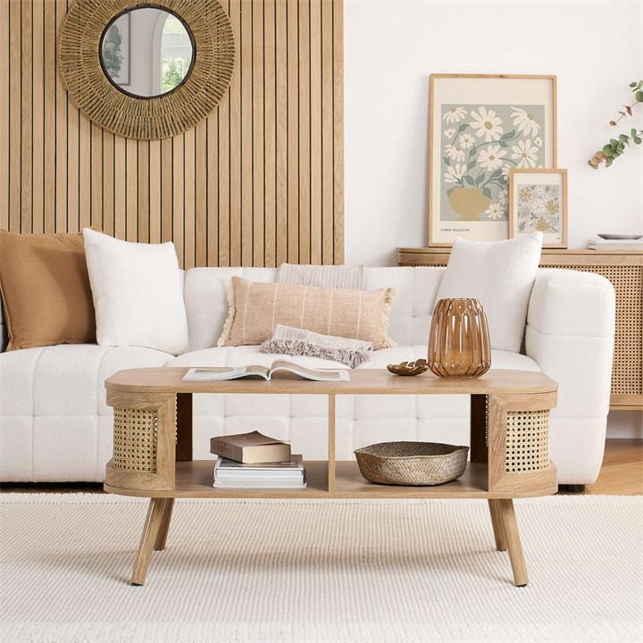 Birlea Rattan Coffee Table in beige features a curved design, natural wood finish, woven rattan storage on sides, and stands on tapered legs, complementing a cozy living space.