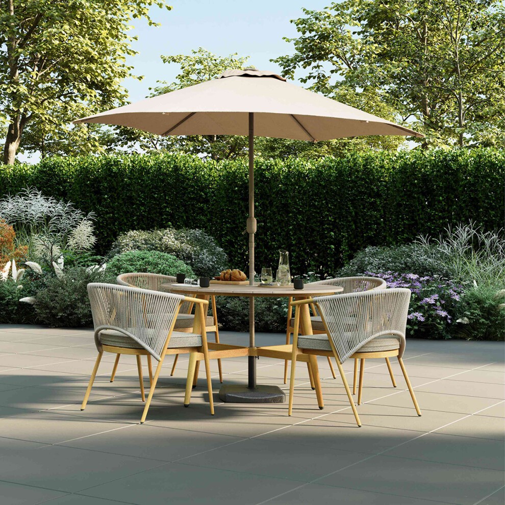 Grey rope weave dining set featuring four stylish chairs and a round table, complemented by a large beige umbrella, set against a lush garden backdrop.