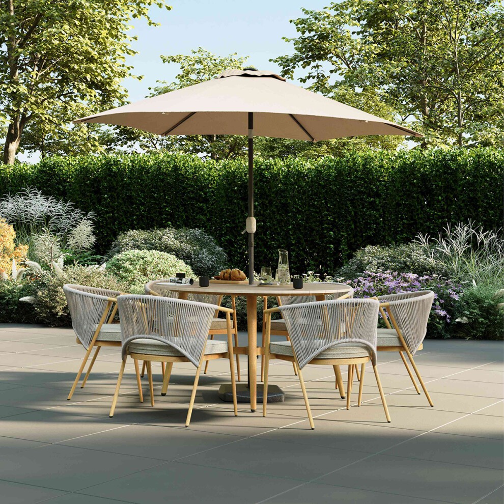 Grey rope weave dining set with six chairs and a round table, featuring a beige umbrella, surrounded by lush greenery and colorful flowers.