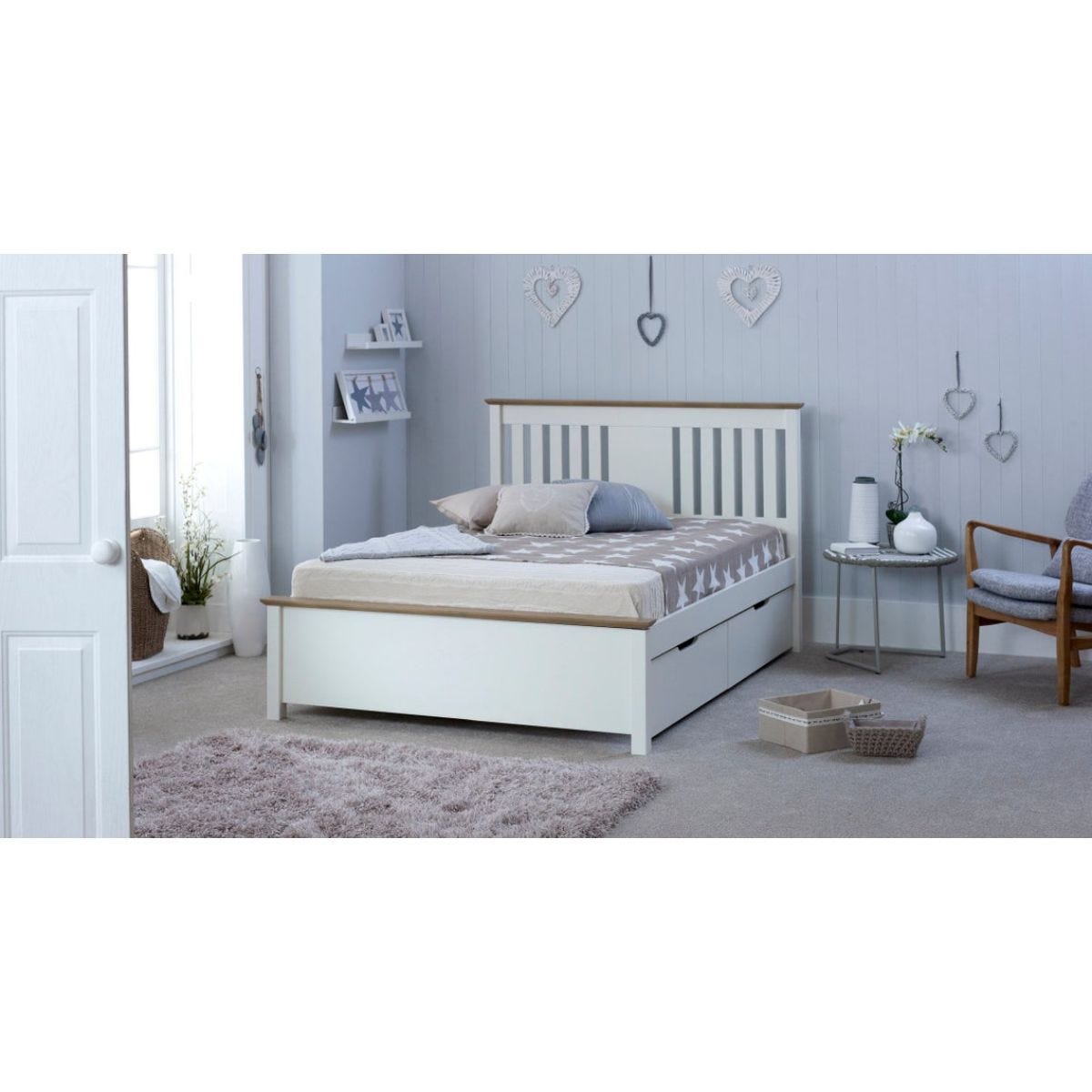 Chester white wooden double bed with a slatted headboard and two storage drawers, set in a softly decorated room with light-colored walls and cozy furnishings.