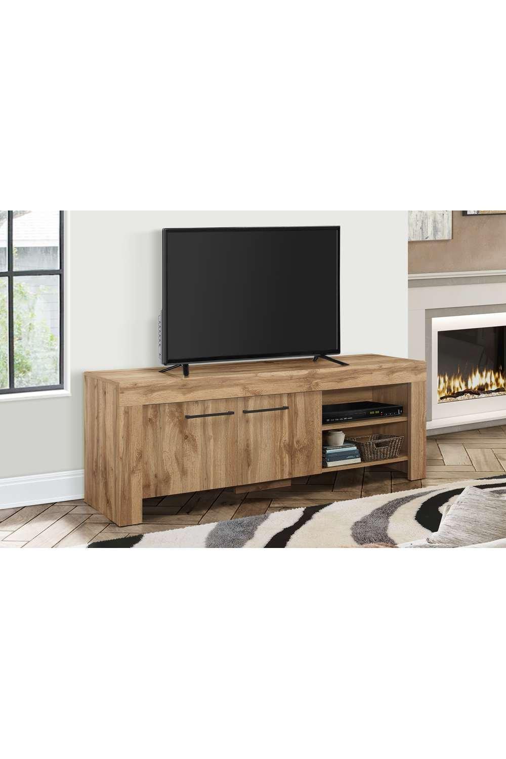 Wide brown oak TV unit with a smooth top, two drawers, and an open shelf, designed for widescreen entertainment, set against a light wall and a cozy fireplace.