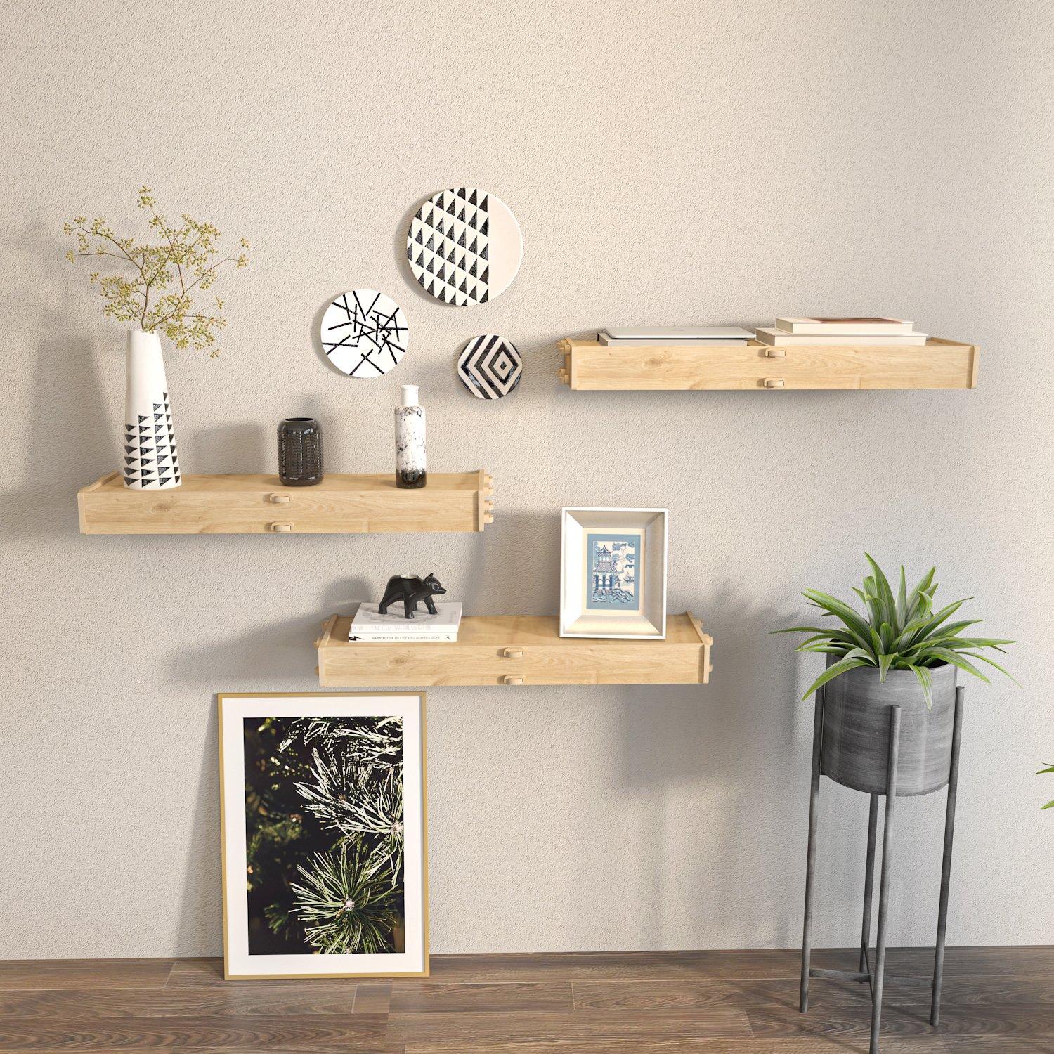 Three wooden wall-mounted shelves in a light natural finish, displaying decorative items, including vases, books, and framed art, against a neutral wall.