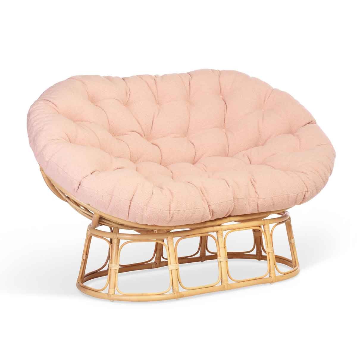 Natural rattan Papasan sofa with a powder pink tufted cushion and a curved brown base, offering a cozy and stylish seating option.