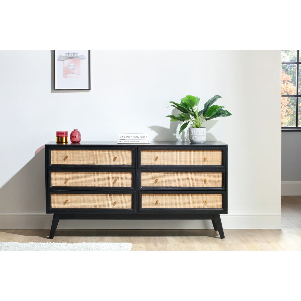 Desser Venice Wide 6 Drawer Rattan Chest Unit features a sleek black frame with natural rattan drawer fronts, six spacious drawers, and stylish tapered legs, set against a bright interior backdrop.