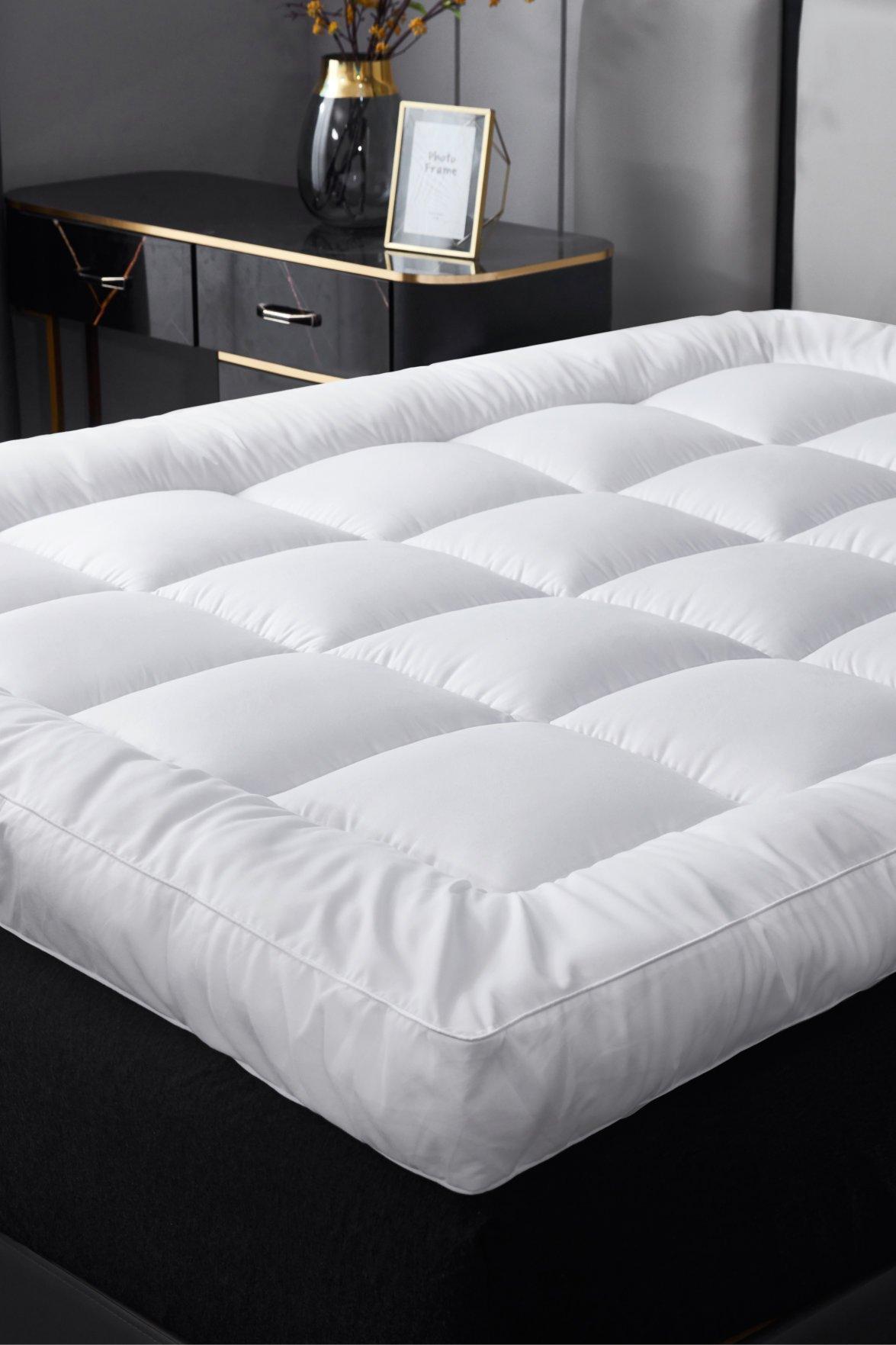 Ezysleep 4-inch thick super soft white mattress topper with a quilted design, placed on a black bed, featuring a modern nightstand in the background.