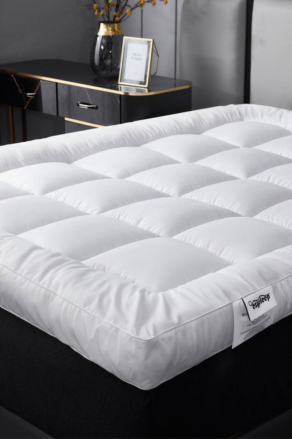 White 4-inch thick super soft mattress topper with a quilted design, featuring a small single size, placed on a dark bed frame with a stylish nightstand in the background.