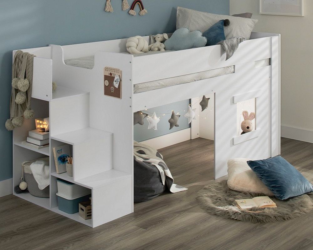 Marlowe Mid Sleeper Bed in white wood features steps, storage shelves, and a cozy play area with a window, decorated with soft cushions and plush toys.