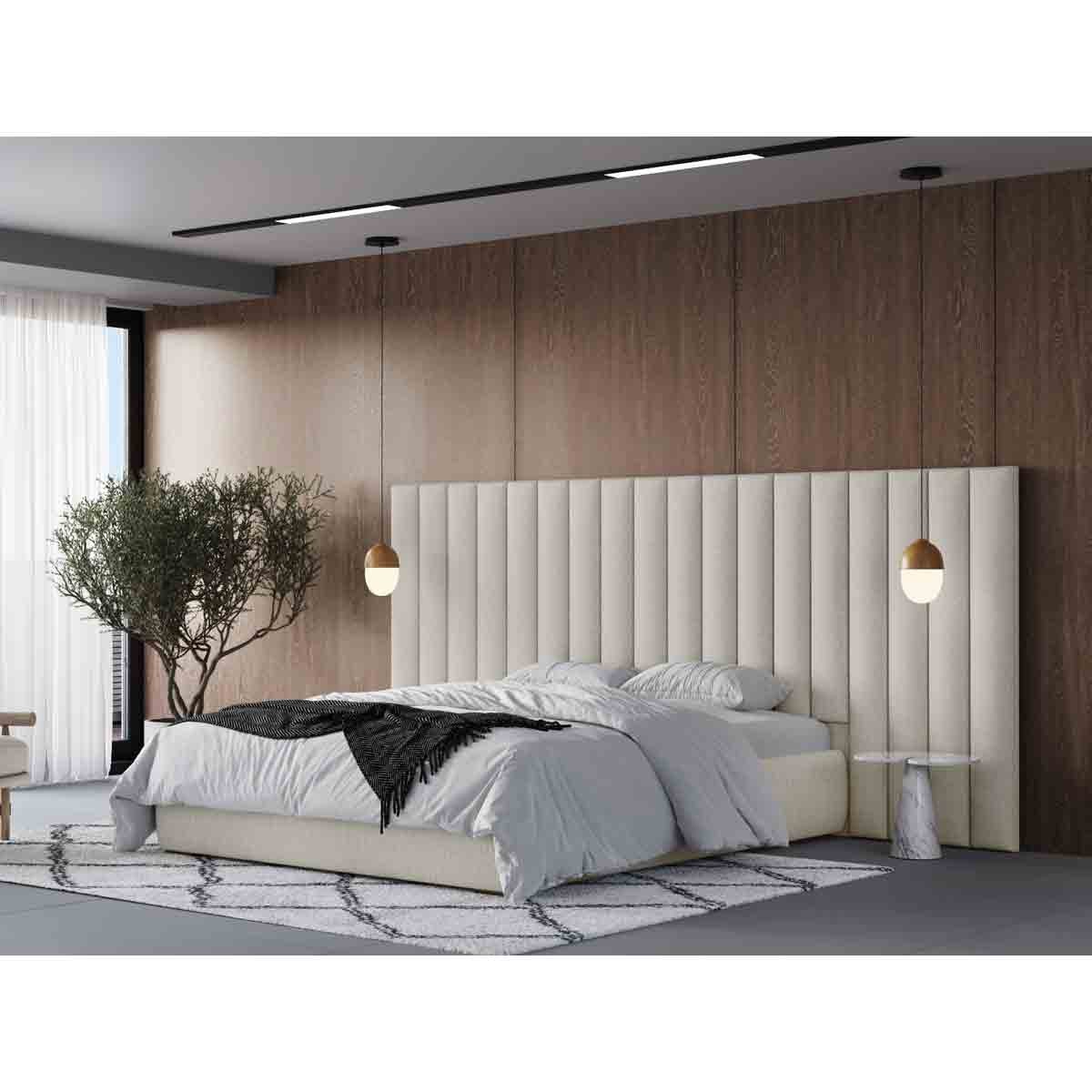Cream king-sized bed with a tall, vertically striped upholstered headboard, paired with a white bedspread and decorative black throw, set against a wooden wall and modern decor.