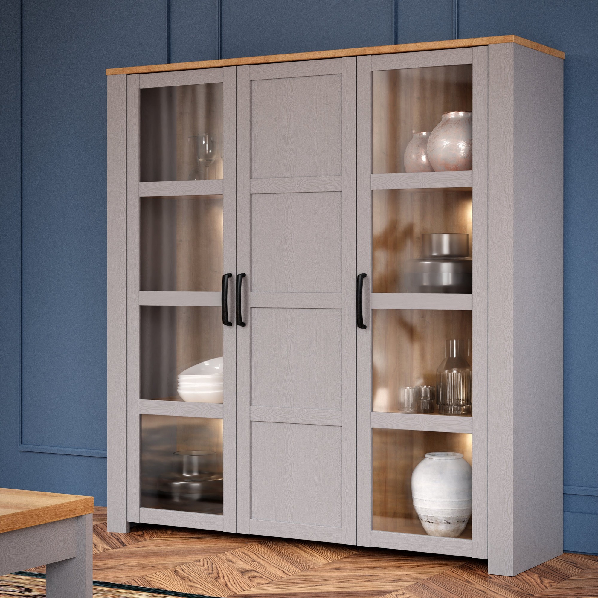 Large light gray display cabinet with four LED lights, featuring glass doors, wooden top, and black handles, showcasing decorative items inside.