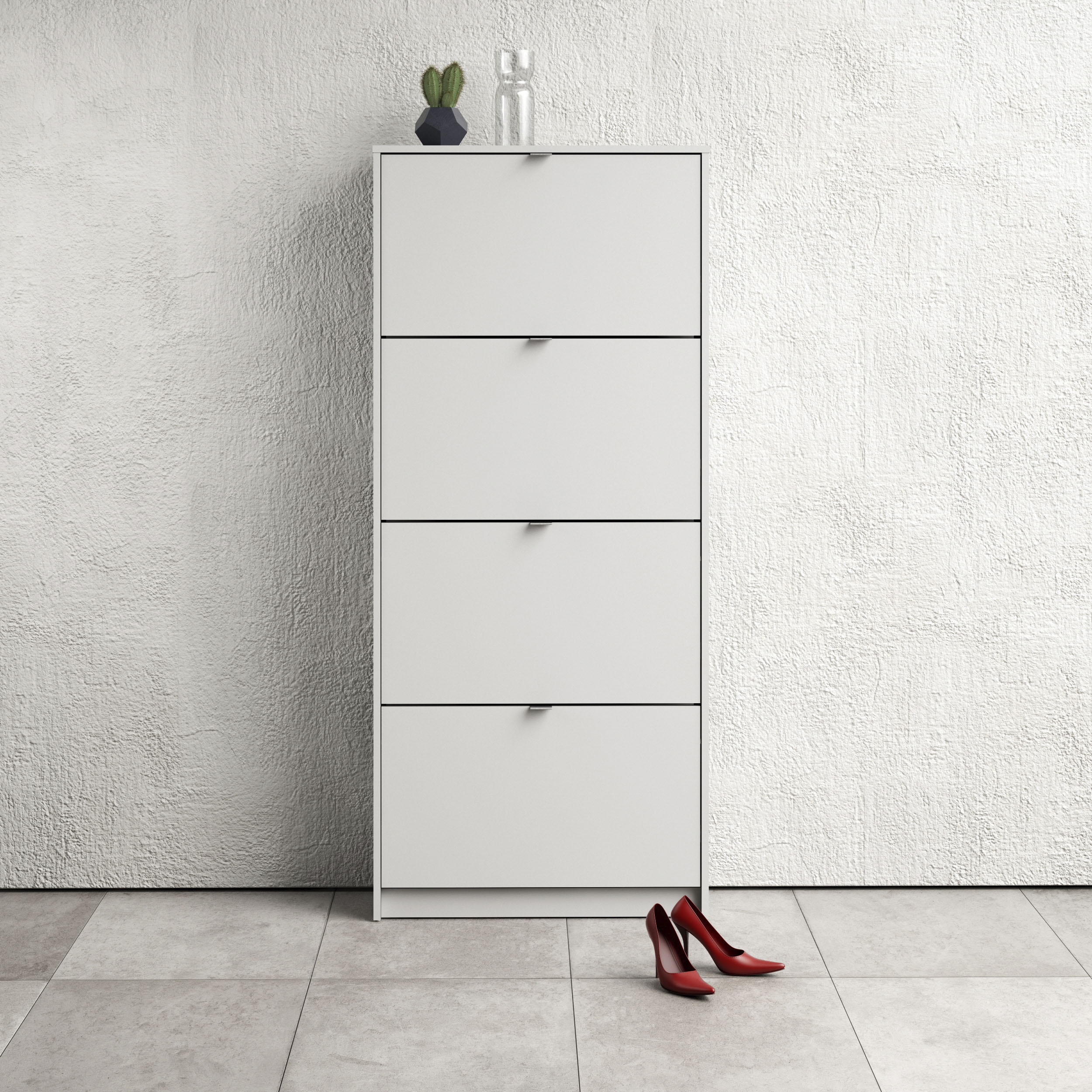 White shoe cabinet with four flip-down doors, two layers, sleek design, minimalistic handles, and red high-heeled shoes placed on the floor beside it.