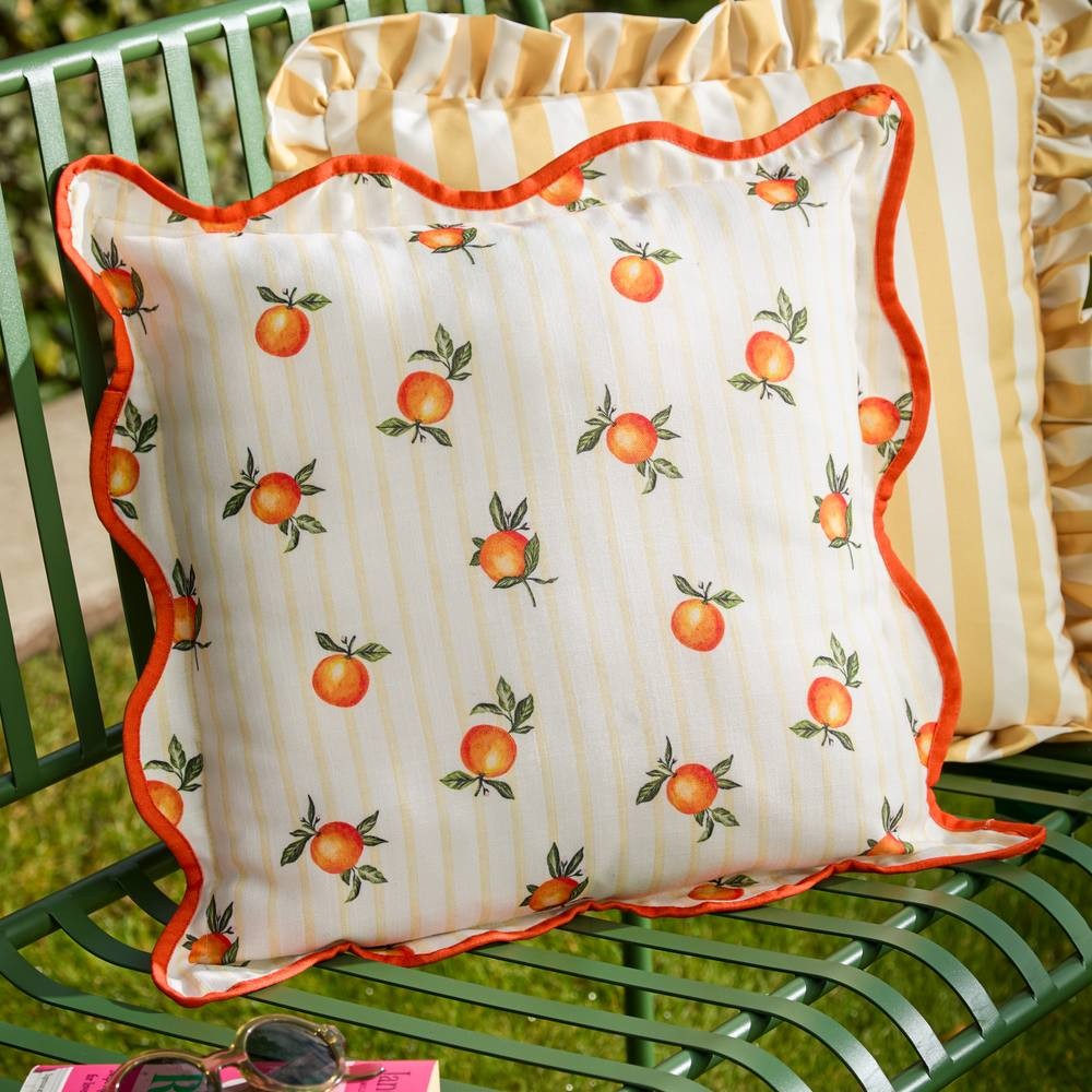 Yellow striped outdoor cushion featuring a vibrant orange fruit pattern, trimmed with a bright orange scalloped edge, made from durable fabric for outdoor use.