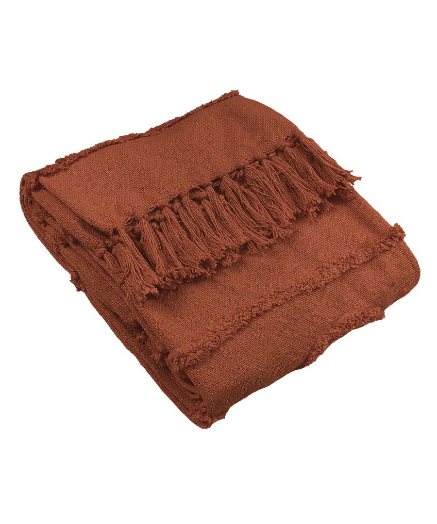 Red cotton throw blanket featuring a textured weave and decorative fringed edges, neatly folded and showcasing a warm, earthy tone.