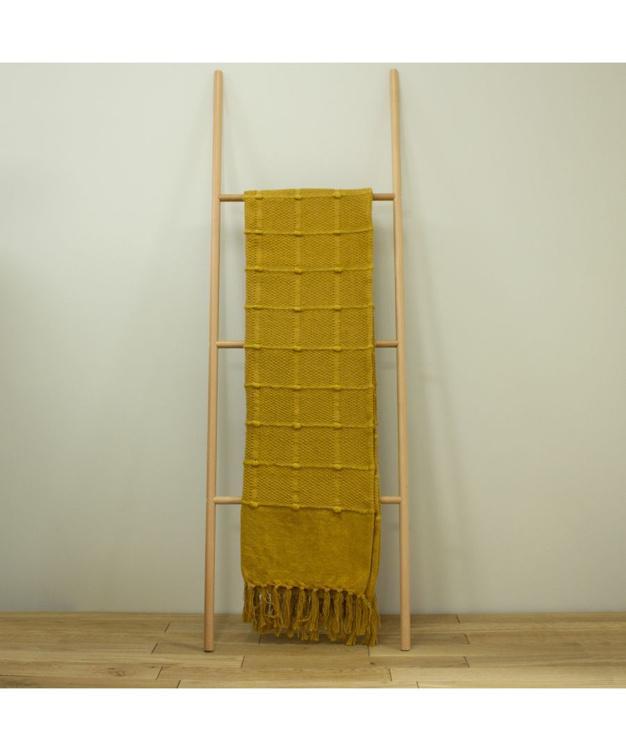 Ochre orange cotton throw measuring 140 cm x 180 cm, featuring a textured pattern and fringed edges, displayed on a wooden ladder against a neutral background.