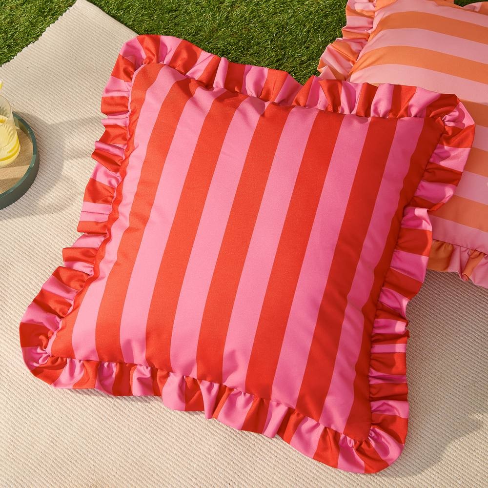 Red and pink striped outdoor cushion with a ruffled edge, featuring a smooth fabric surface, perfect for adding a pop of color to outdoor seating.