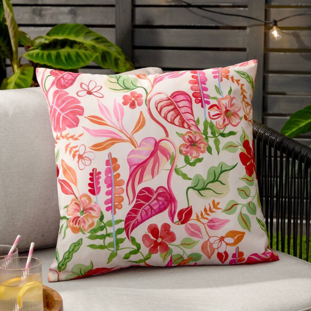 Tropical floral cushion featuring vibrant pink, orange, and green patterns on a natural background, designed for outdoor use with a soft fabric finish.