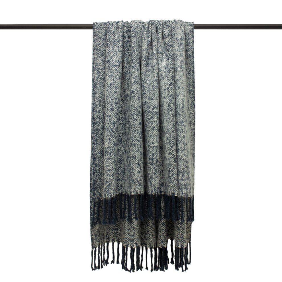 Navy and cream woven herringbone throw with fringed edges, made from soft material, draped elegantly on a hanger.