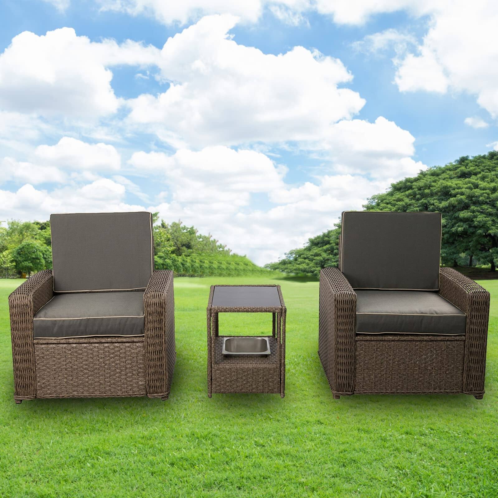 Brown wicker 3-piece patio furniture set featuring two armchairs with gray cushions and a matching ice bucket coffee table, set against a grassy outdoor backdrop.