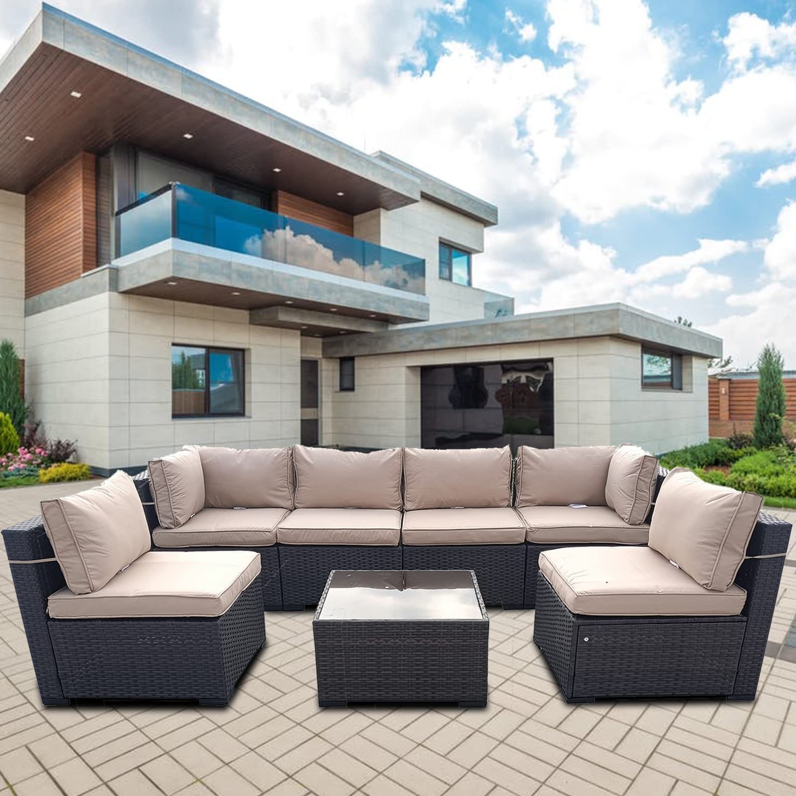 Brown rattan 10-piece modular outdoor recliner sofa with beige cushions, featuring a glass-top coffee table, set against a modern house backdrop.