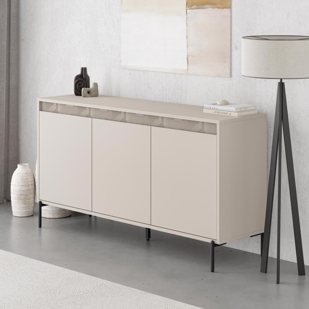 Large beige sideboard with three doors, featuring a smooth sandstone finish, sleek design, and black metal legs, complemented by decorative items and a modern lamp.
