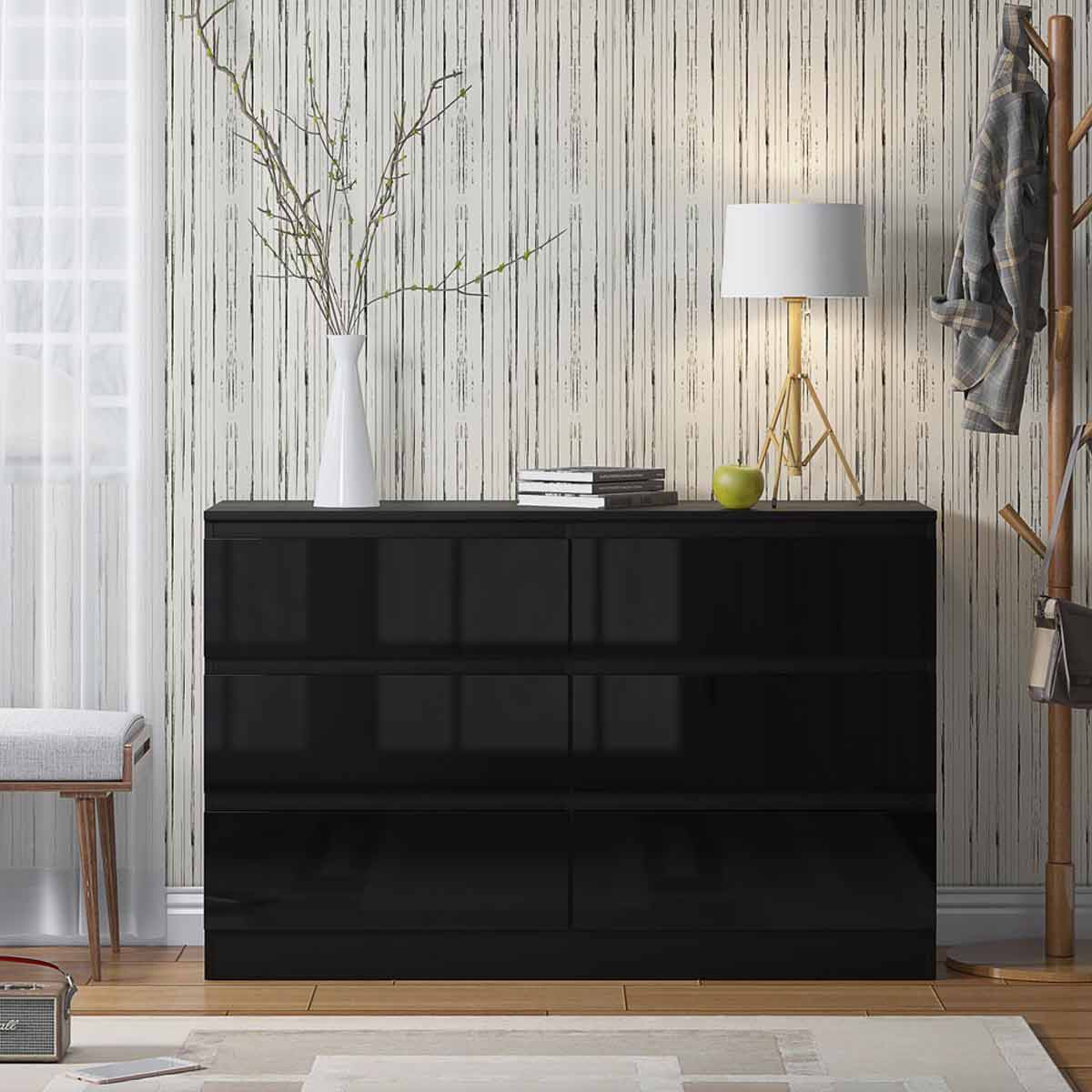 High gloss black chest of drawers with six spacious drawers, sleek design, set against a textured wall, accompanied by a white lamp and decorative items.